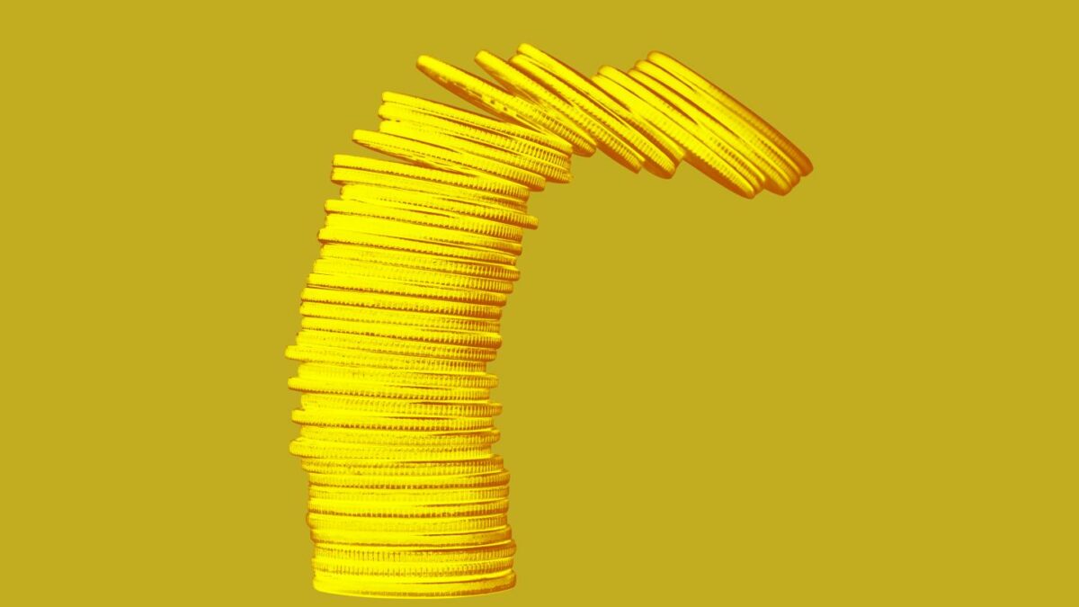 A stack of coins tumbles over on top of a solid background.