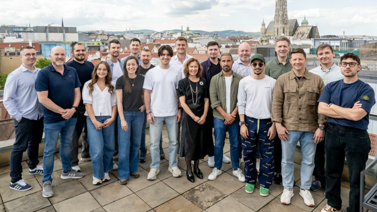 19 of Cyclops' members stand smiling at the camera from their offices in Vienna, Austria.