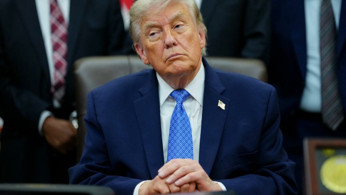 US President Donald Trump sits in silence with his hands folded on top of each other.
